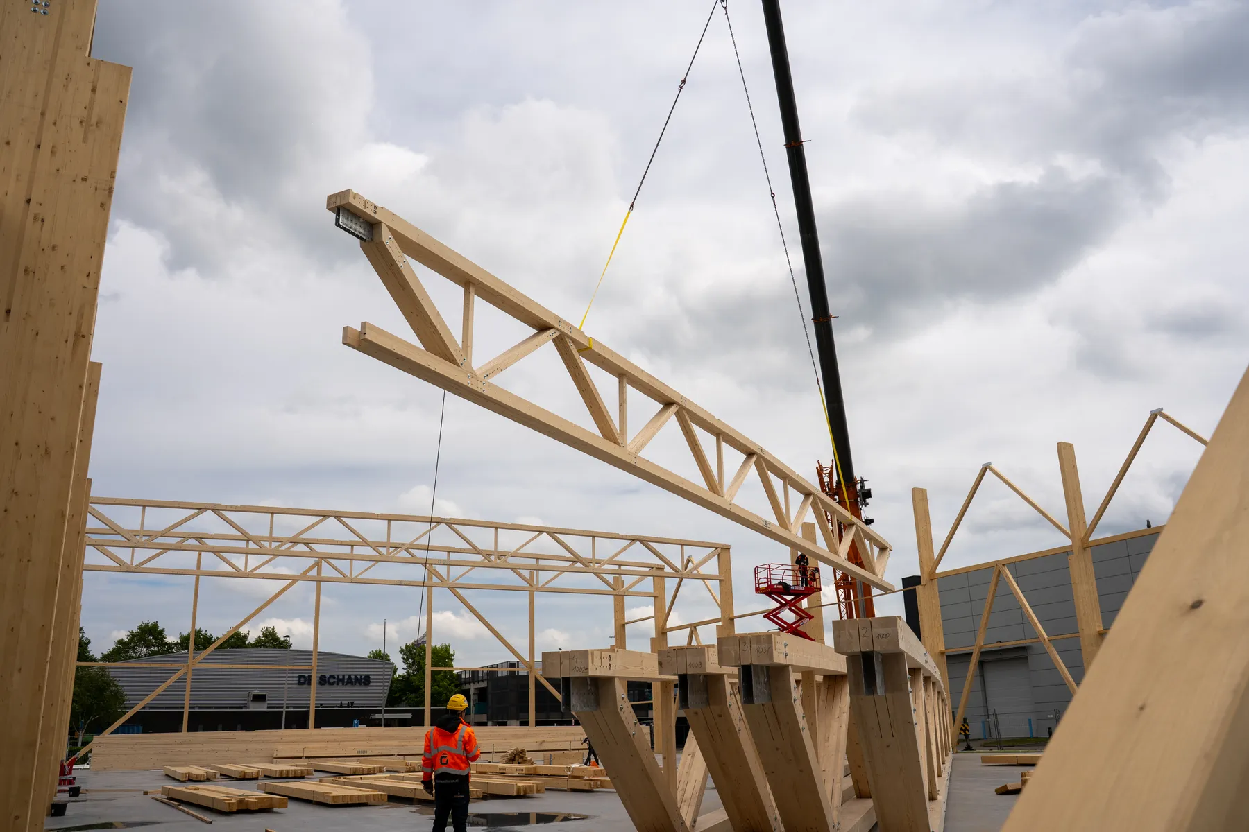 Kran hebt einen Holz-Fachwerkbinder auf der Baustelle ein, Montage durch LIGNA systems